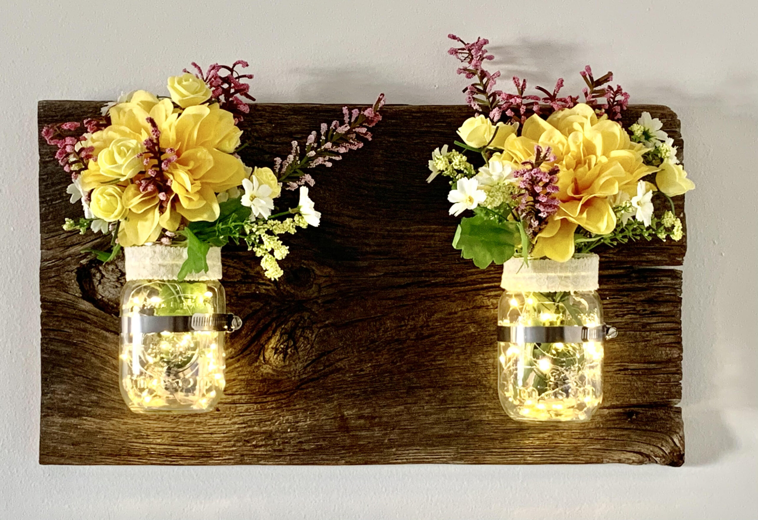 Jars of lights with flowers attached to stunning barn board
